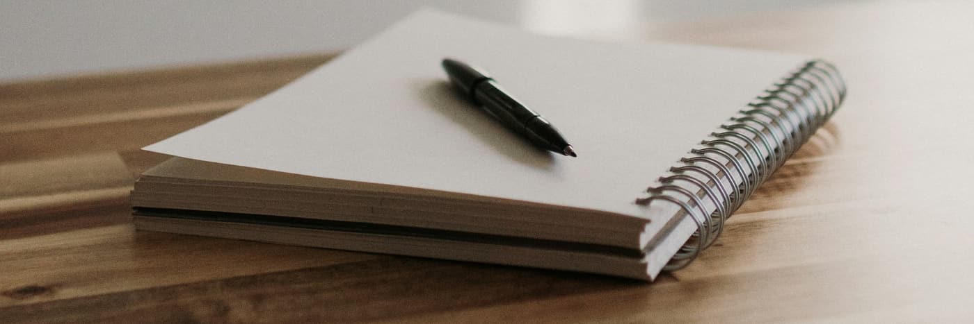 An open notebook and pen on a wooden table